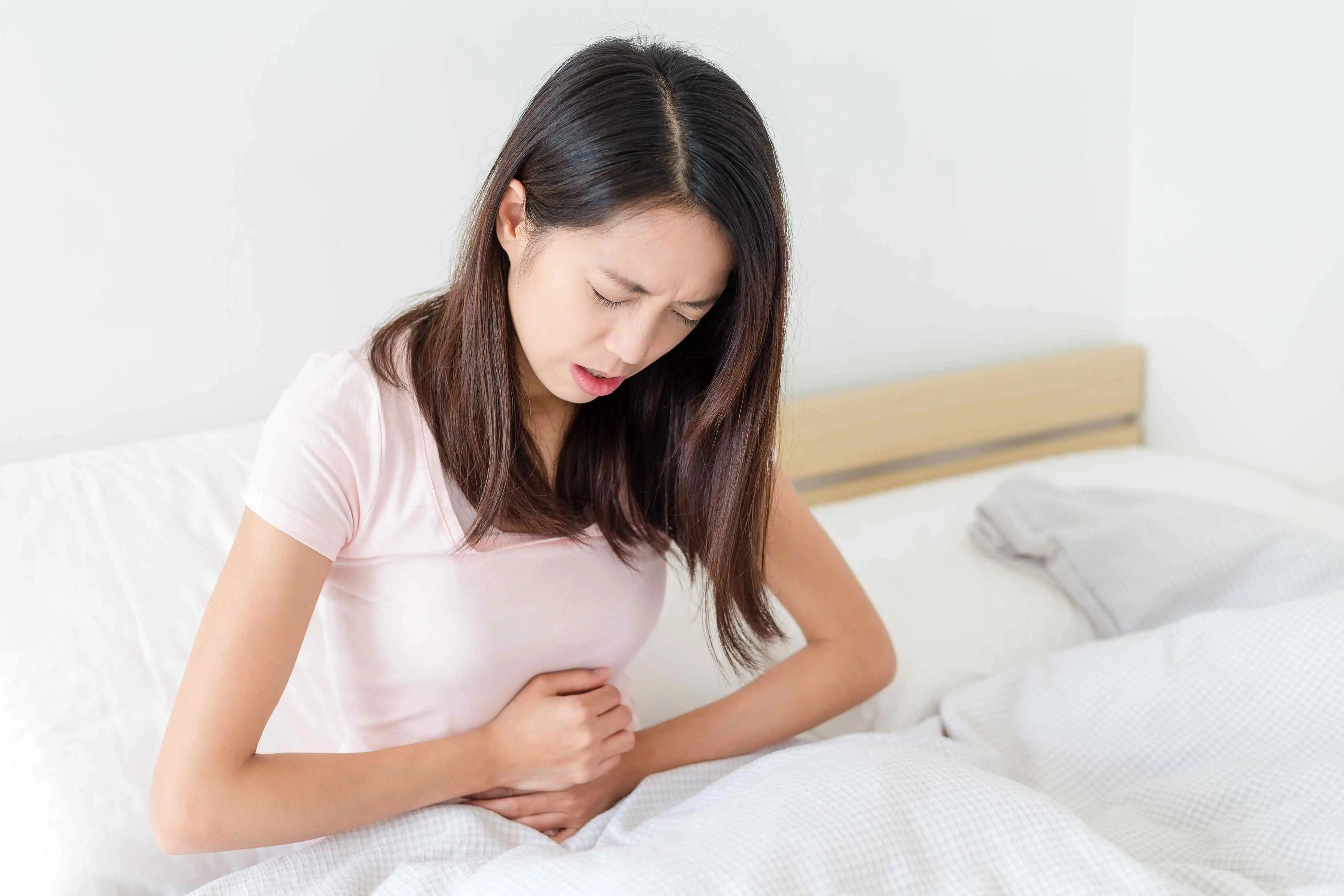 woman in stomach pain - How to know if the infection from your tooth abscess is spreading